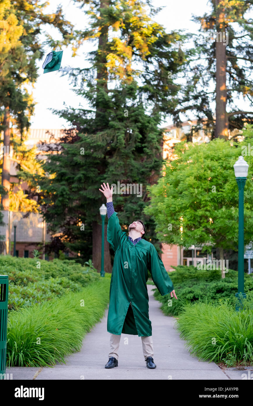 College grad studente gettando hat in aria prima di cerimonie di laurea. Foto Stock