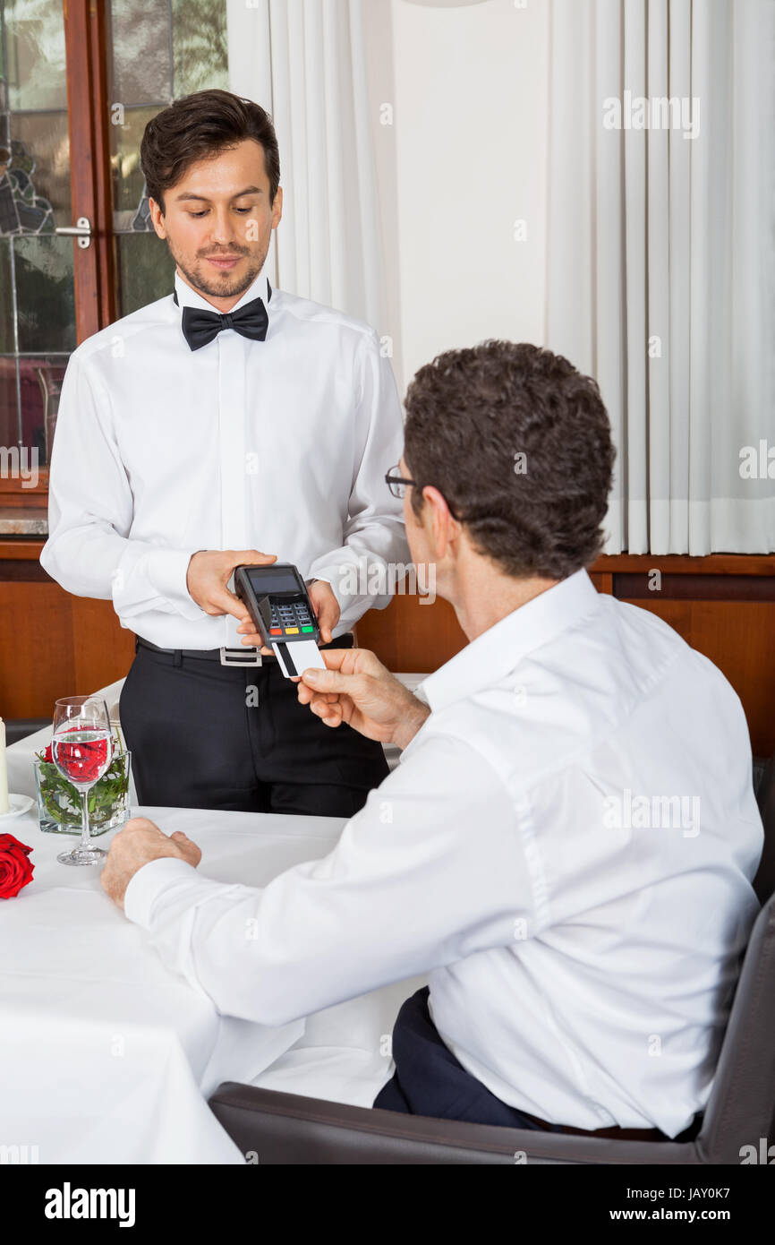 Bargeldlose zahlung im restaurant mit kreditkarte abendessen paar geld Foto Stock