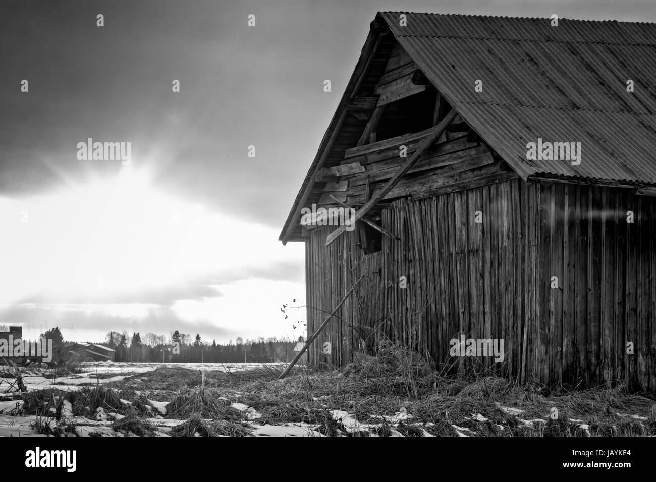 La primavera sole tramonta dietro un vecchio fienile casa nel nord della Finlandia. La neve ha cominciato a fondere e i giorni sono un po' più caldo. Foto Stock