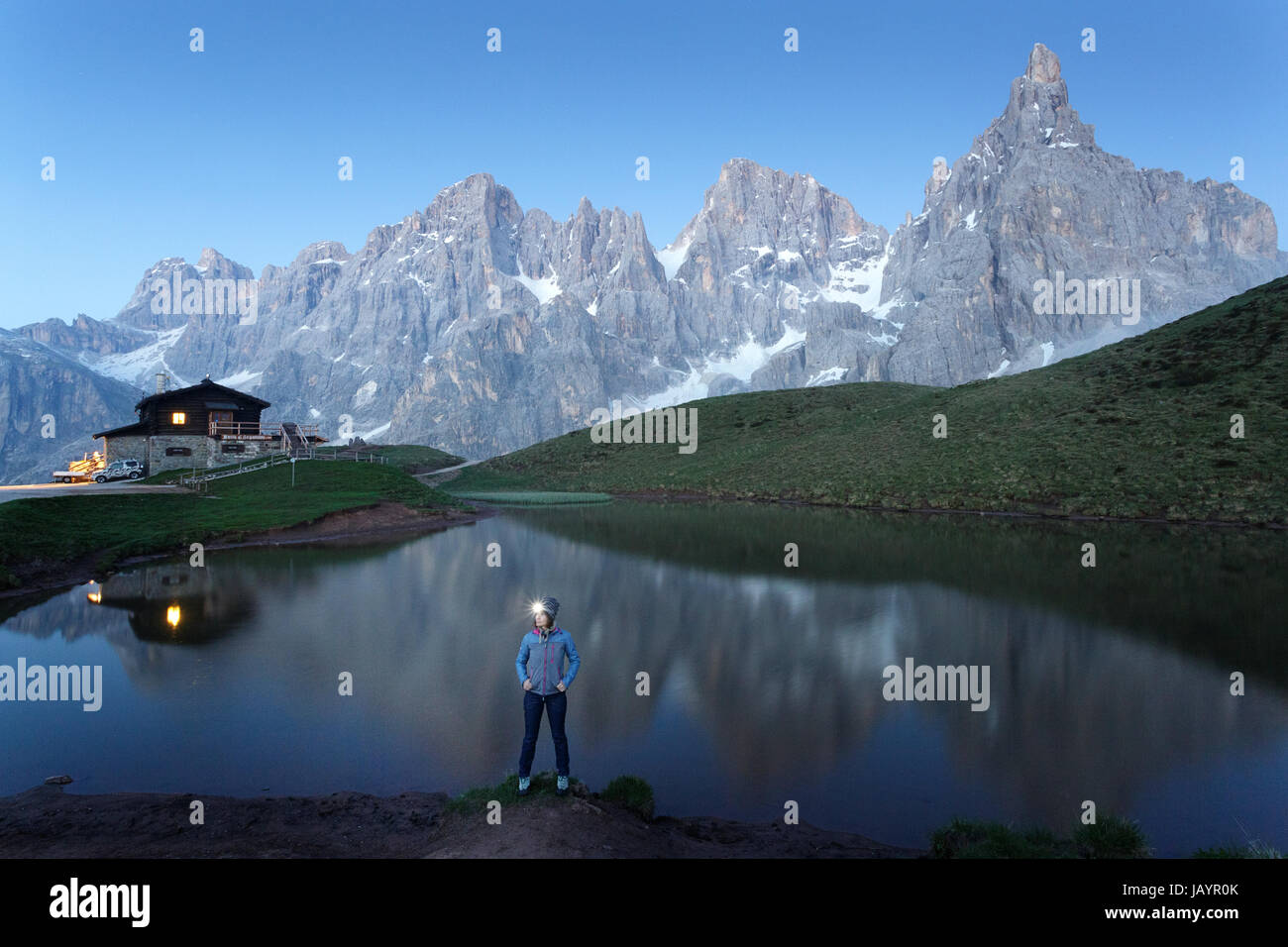 Donna in piedi presso il lago al Rifugio Segantini con una torcia da testa, Dolommites, Italia. Foto Stock
