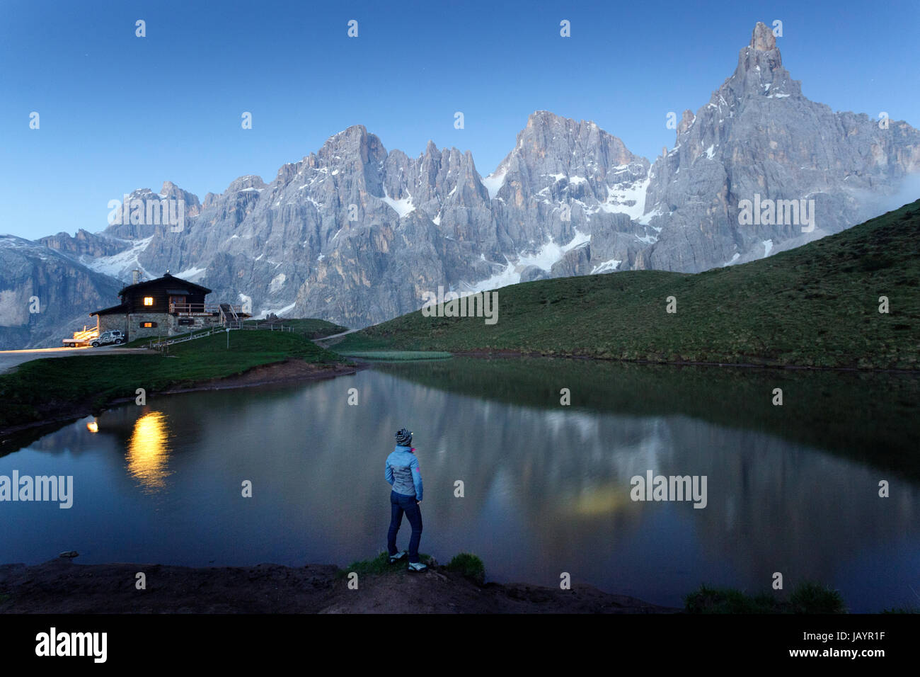 Donna in piedi presso il lago al Rifugio Segantini con una torcia da testa, Dolommites, Italia. Foto Stock