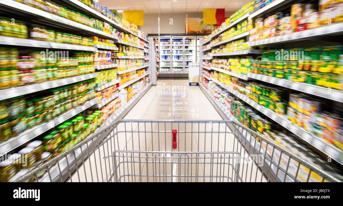 Un vuoto Carrello spesa tra le file di scaffali del supermercato. Foto Stock