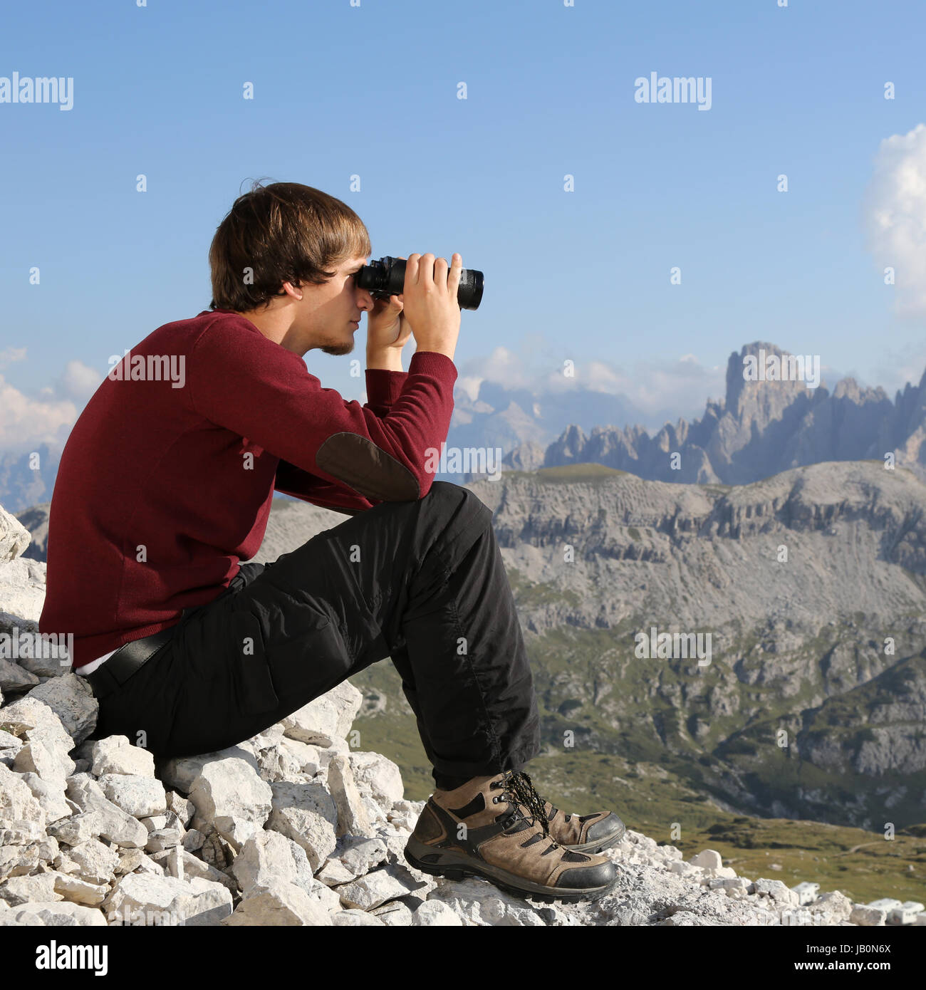 Ein junger Mann schaut durch ein Fernglas und sucht das Ziel Foto Stock