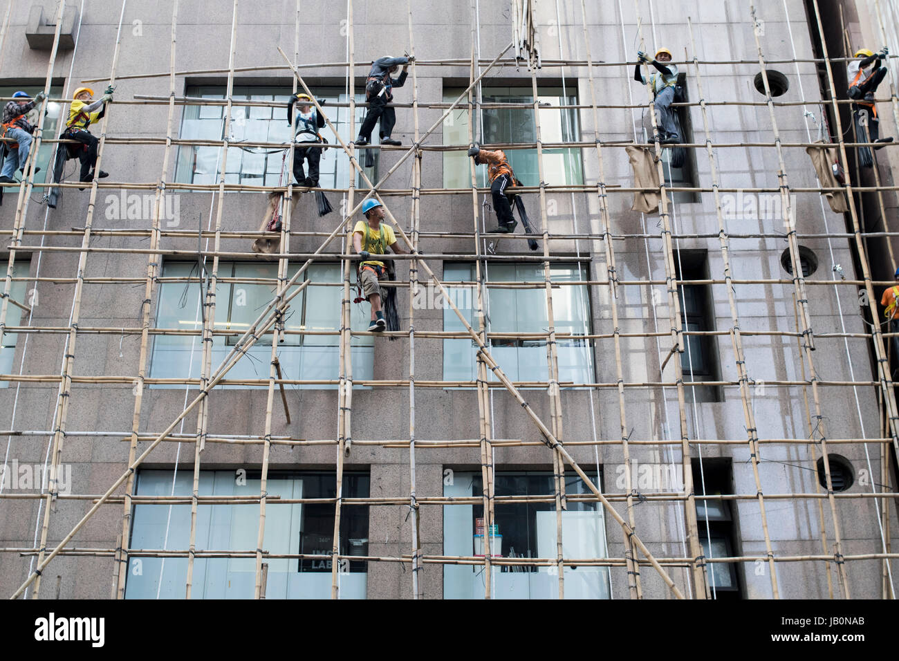 Lavoratori costruire impalcature di bambù al di fuori di un edificio. . Foto Stock