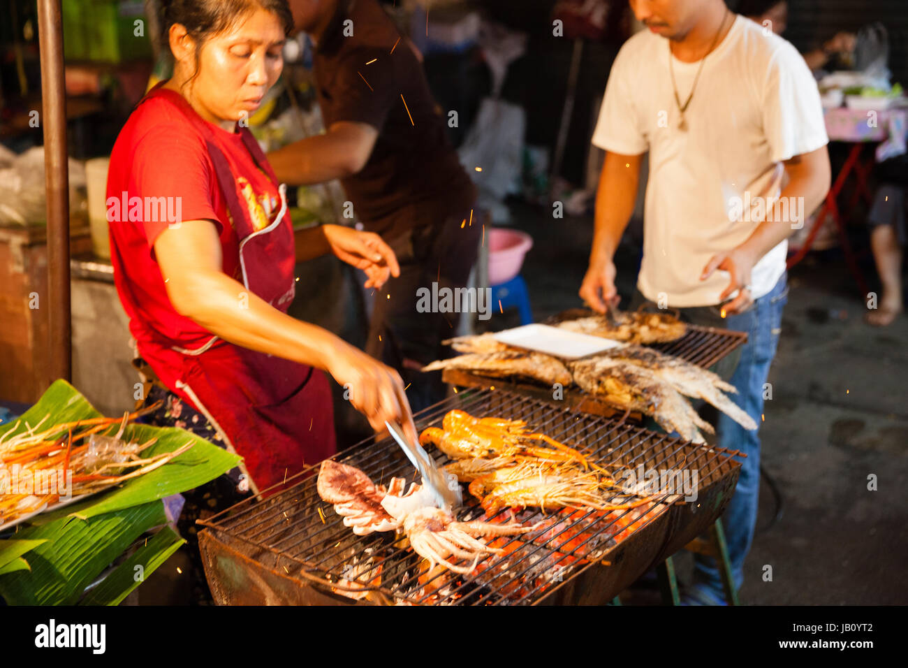 CHIANG MAI, Thailandia - 27 agosto: Donna cuochi di scampi e calamari alla griglia al mercato di domenica (walking street) il 27 agosto 2016 a Chiang Mai, T Foto Stock