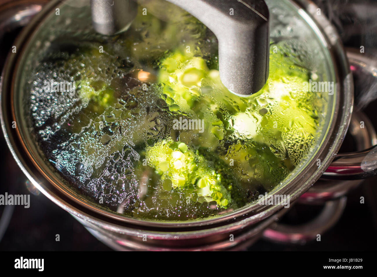 La cottura a vapore di verdure in una pentola con coperchio vetro Foto Stock