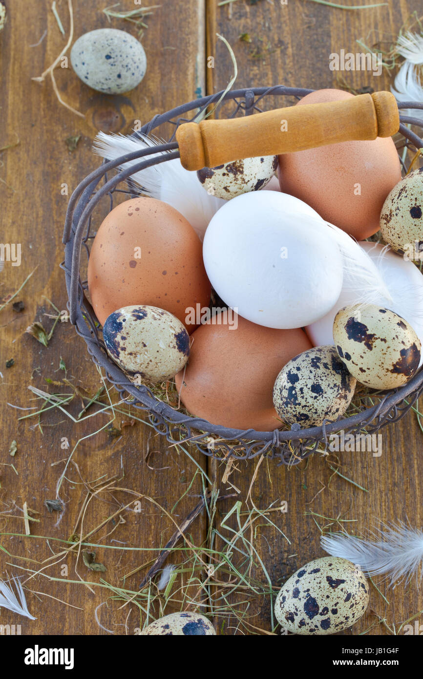Vintage Drahtkorb mit verschiedenen rohen Eiern zu Ostern Foto Stock