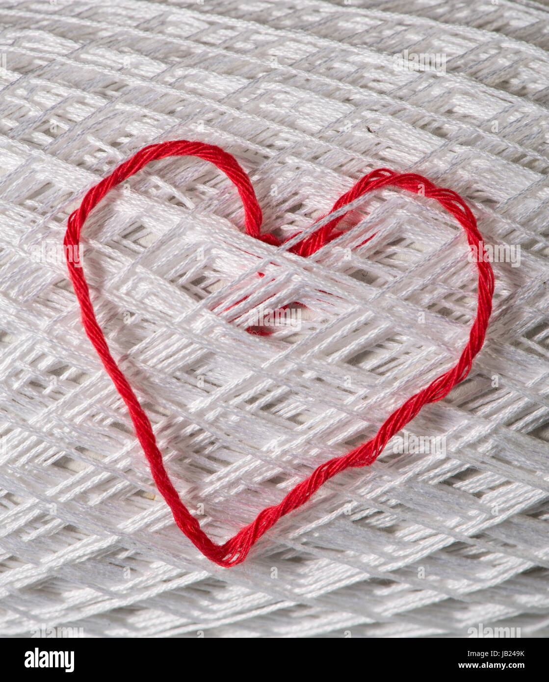 Maglia cuore rosso su bianco palla di filato. Foto Stock