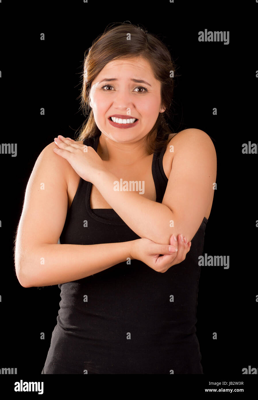 Bella giovane donna con il gomito il dolore, in sfondo nero. Foto Stock