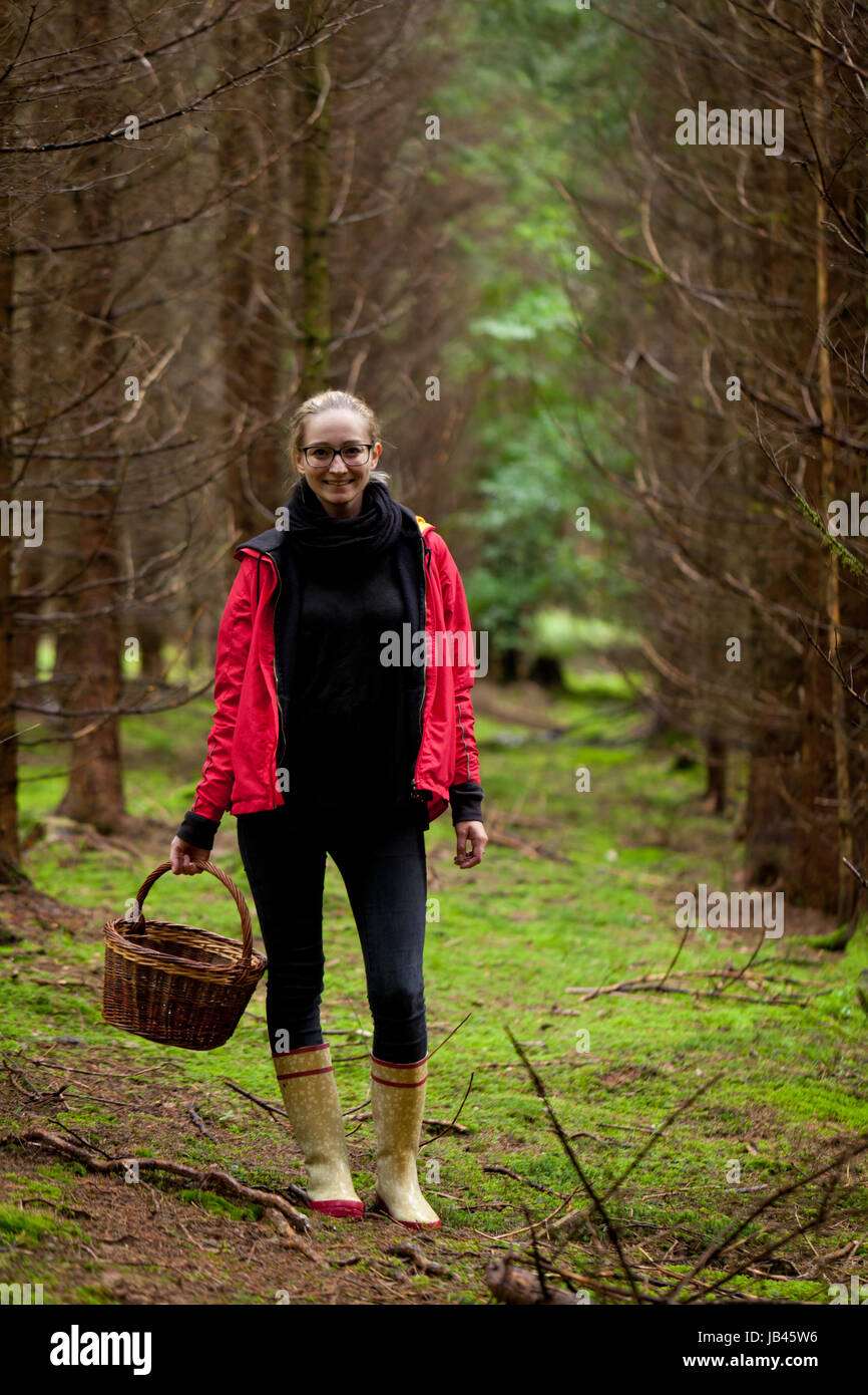 Junge frau mit roter jacke im herbst sammelt pilze im Wald natur entspannung lebensmittel Foto Stock