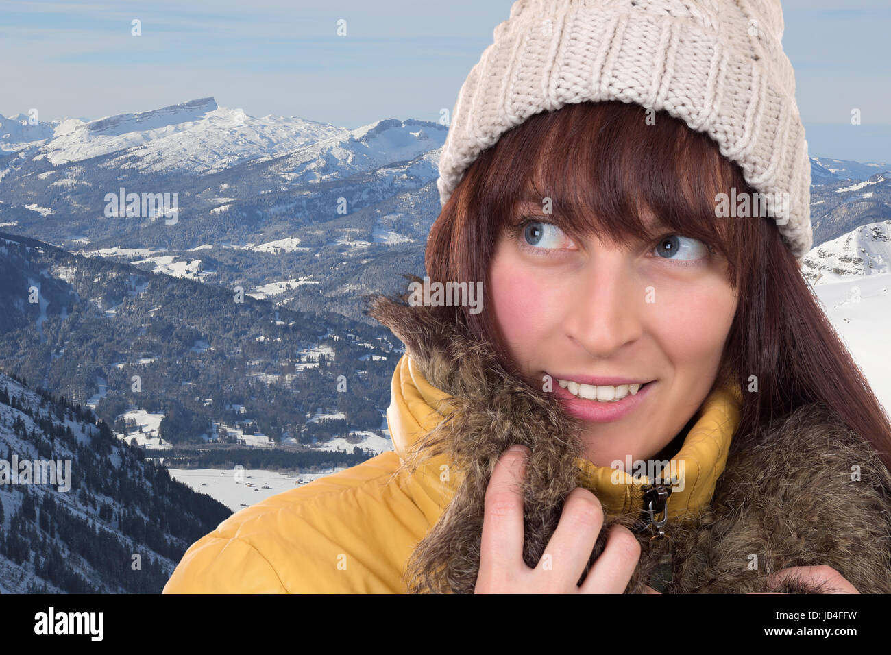 Junge Frau schaut in den Schnee bedeckten Bergen im Winter nach oben Foto Stock
