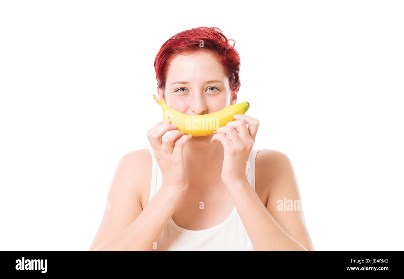 Junge frau hält banane als lächeln Vor den mund vor weißem hintergrund Foto Stock