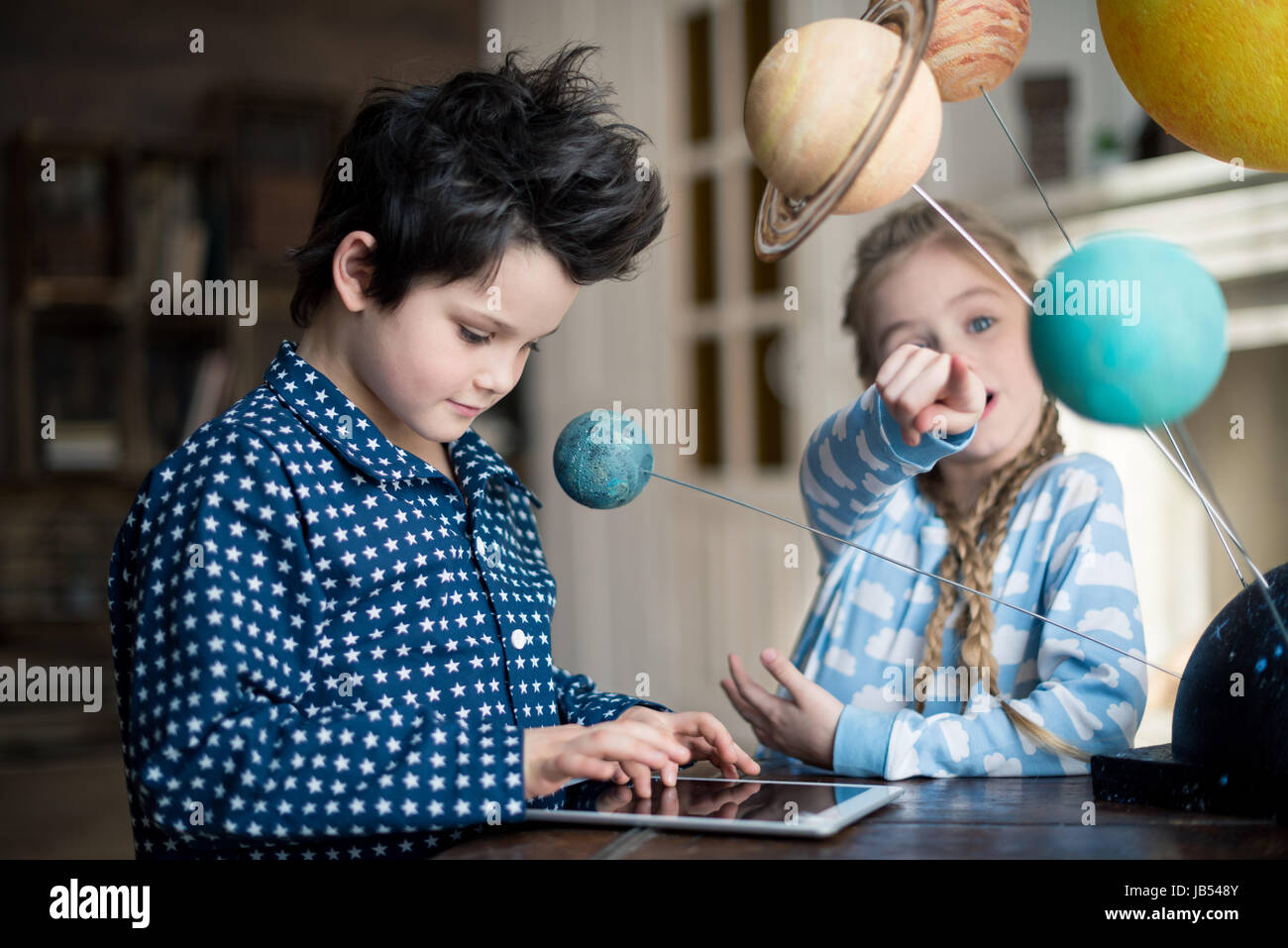 Ragazzo con tavoletta digitale mentre la ragazza puntando sul sistema solare modello Foto Stock