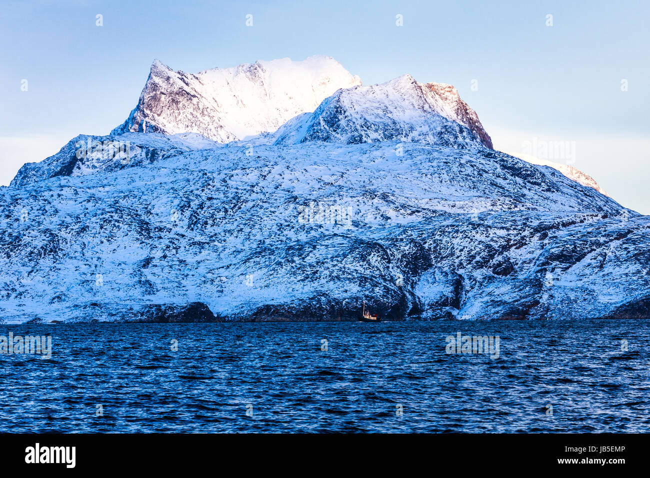 Sermitsiaq enorme montagna coperta di neve con il blu del mare e il piccolo fidhing barca in primo piano, la vicina città di Nuuk, Groenlandia Foto Stock