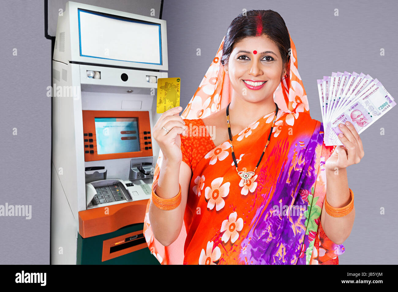 Happy 1 rurale indiano donna in piedi bancomat e trattenere una carta di debito e di rupie Note mostra Bancomat ritirare il concetto di denaro Foto Stock