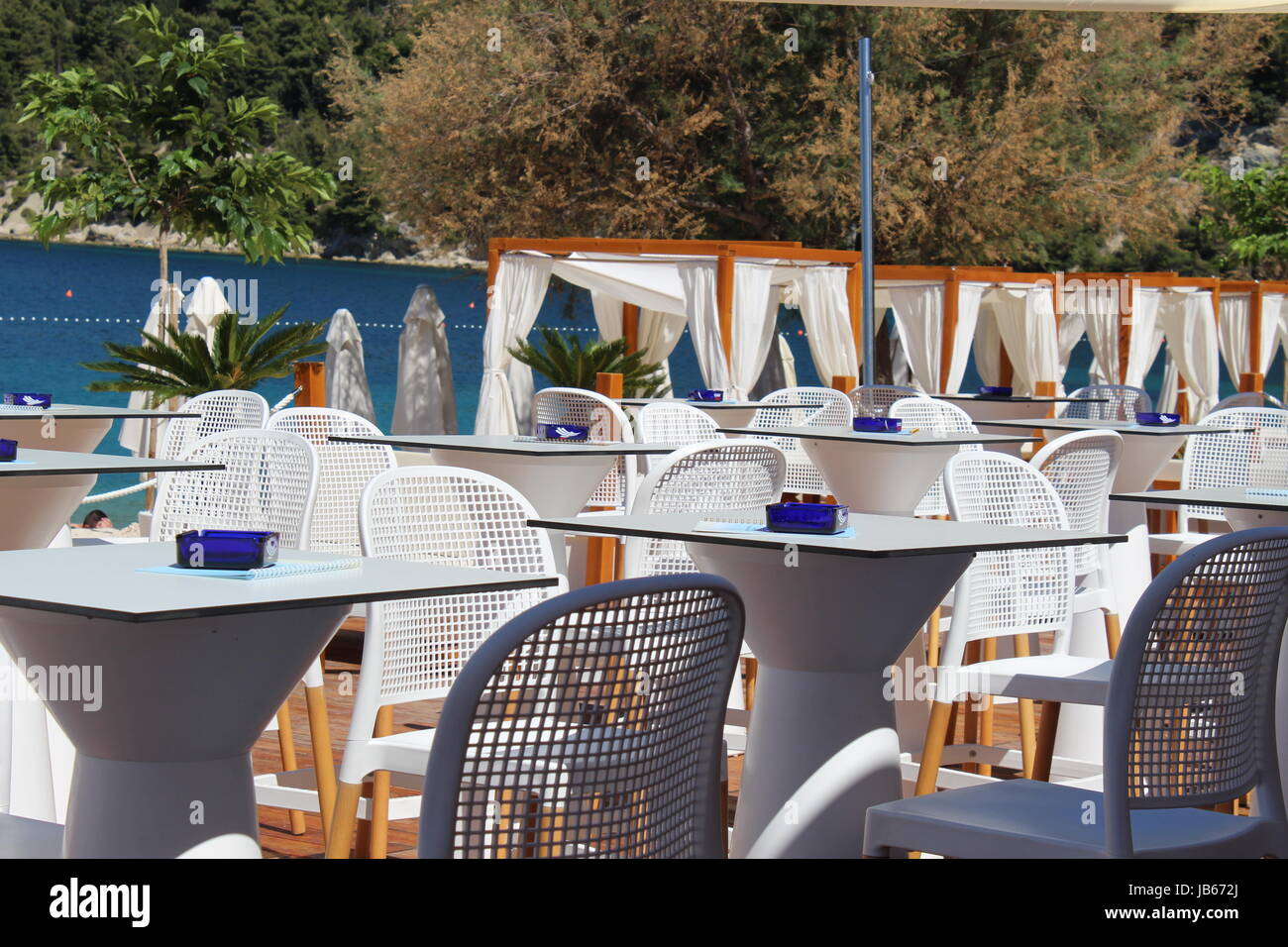 Idilliaco ristorante sulla spiaggia con tavoli bianchi e tettoie in Marjan vicino a Spalato, Croazia Foto Stock