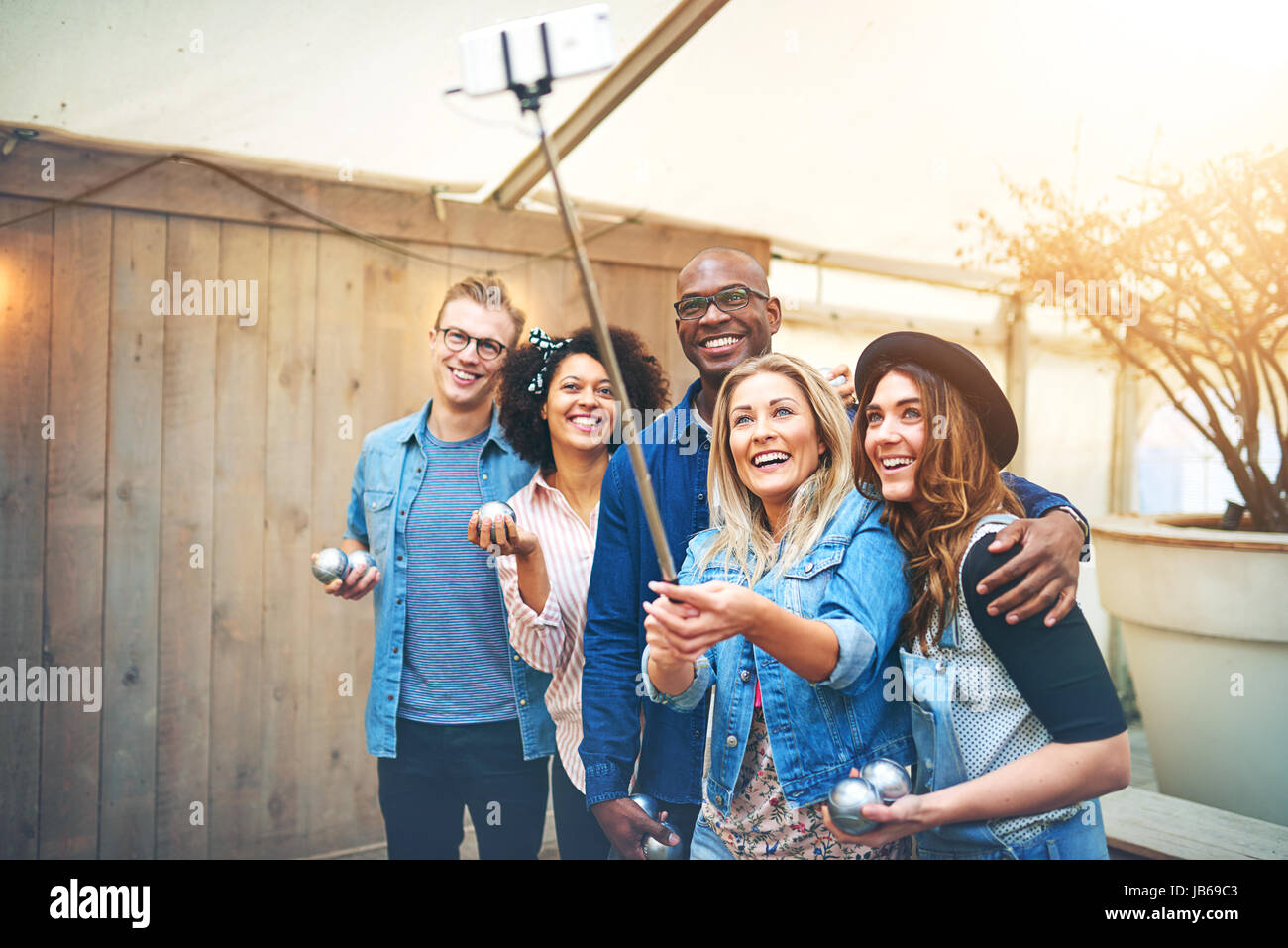 Gruppo sorridente di bianco e nero di uomini e donne che posano con le palle di bocce per selfie e sorridente. Foto Stock