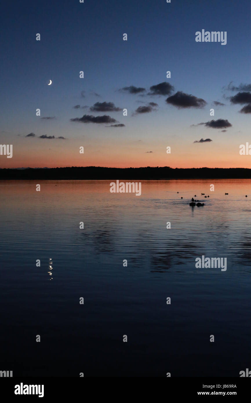 Bellissimo tramonto riflesso sul lago in Azur, in Francia con il cielo stellato di notte e la luna crescente Foto Stock