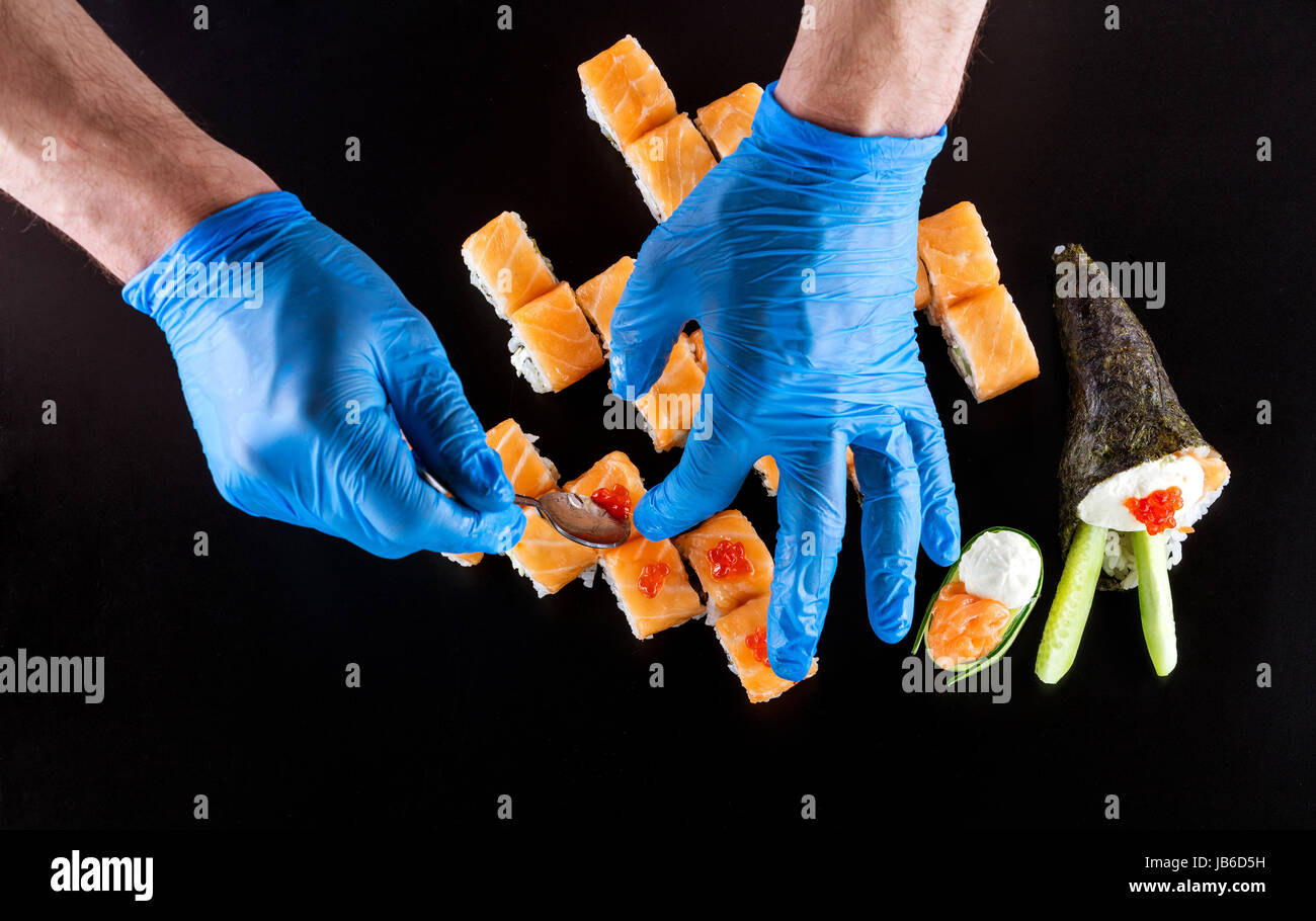 Vista ritagliata della chef prepara sushi su sfondo nero Foto Stock