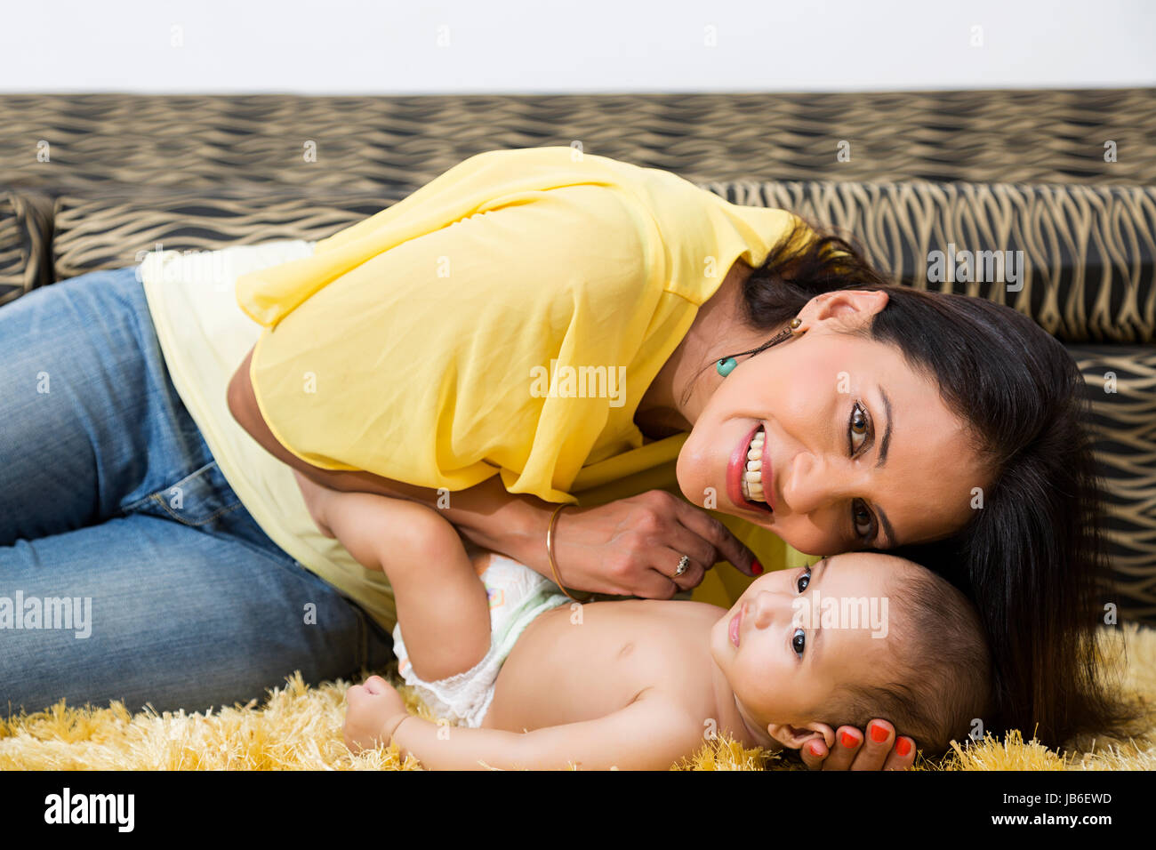 2 persone donna adulta a casa baby boy madre giocoso rug figlio stare insieme Foto Stock