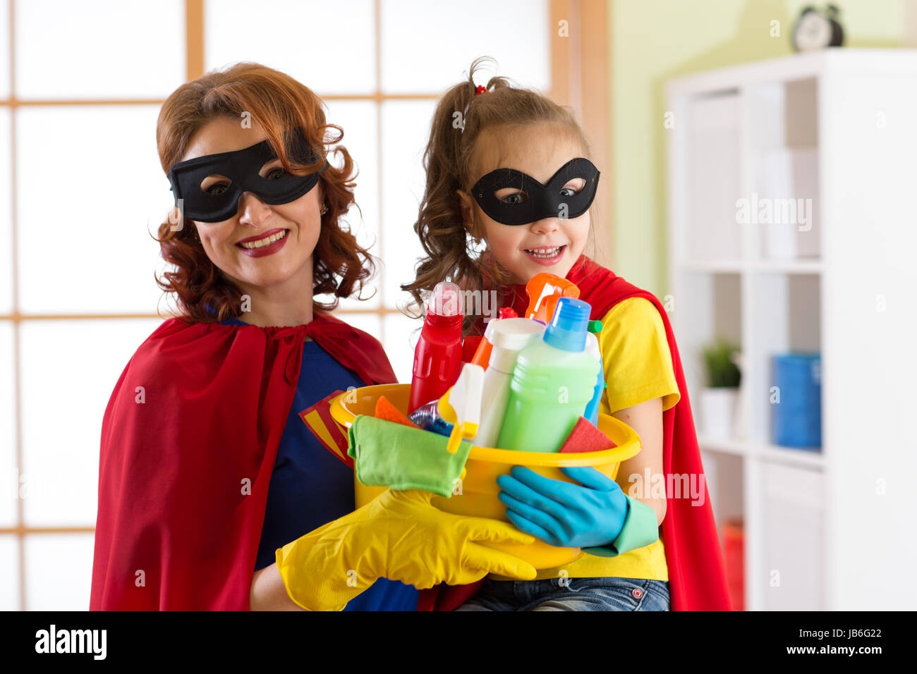 Madre e figlia in costume da supereroe. Mamma e Bambino pronto per la pulizia della casa. Houseworking e il servizio di pulizie. Foto Stock