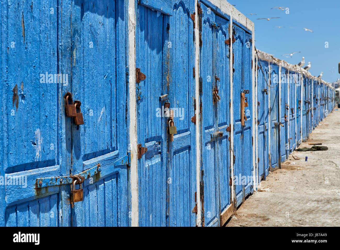 Weathered legno porte blu in fila dalle attrezzature di pesca capannoni Foto Stock