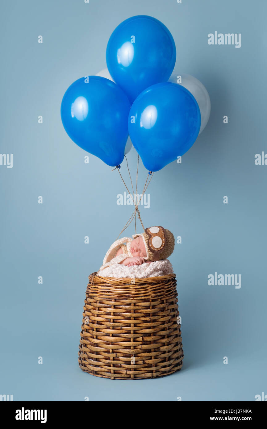 Dormire nove giorni di età neonato ragazzo che indossa un aviatore hat e dormire in una finta mongolfiera. Foto Stock
