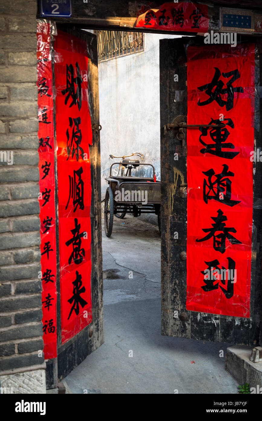 Tipicamente decorate casa porta per fortuna e di biciclette con carrello, Qufu, provincia di Shandong, Foto Stock