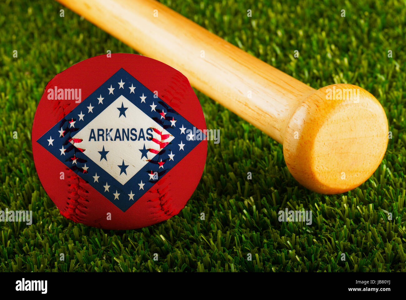 Il baseball con Arkansas bandiera e bat su uno sfondo di erba verde Foto Stock