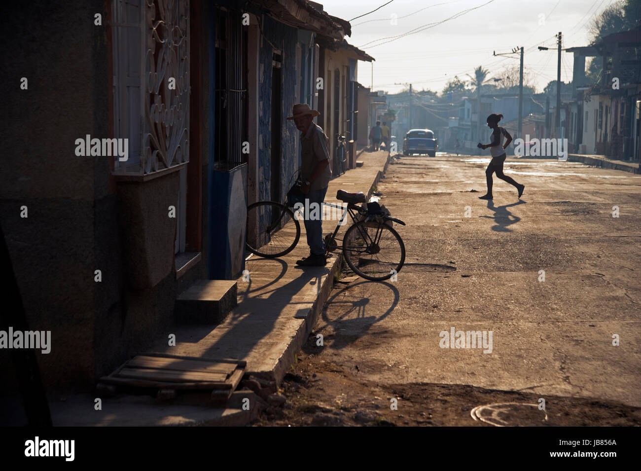 Un vecchio uomo cubani che arrivano a casa sulla sua bicicletta come il sole tramonta in Trinidad, Cuba Foto Stock