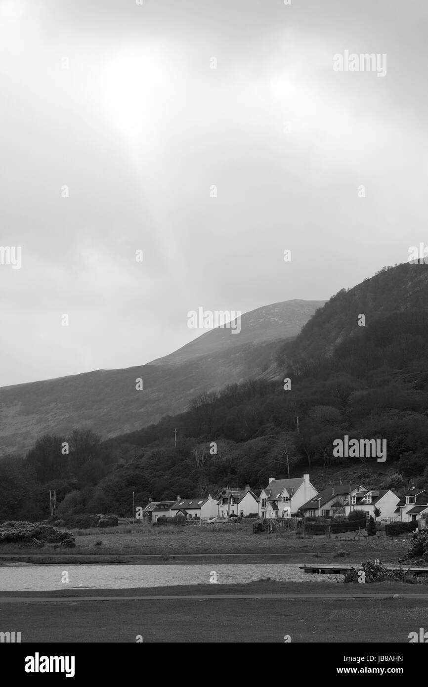 Bianco e Nero paesaggio del villaggio Lochranza, colline e sottili raggi di sole. Nord Arran, Scozia, aprile 2017. Foto Stock
