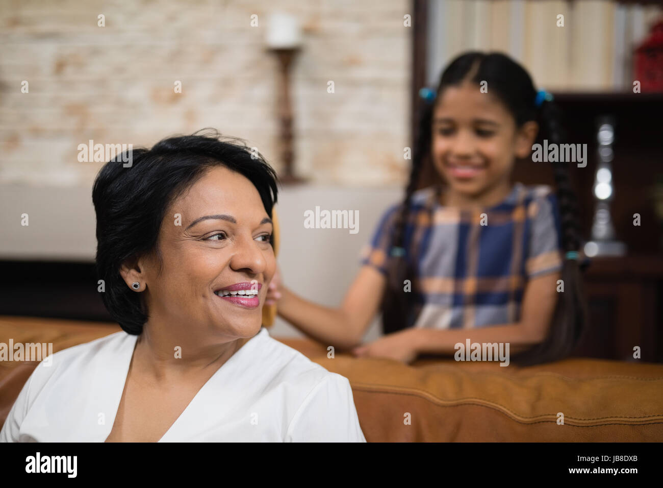 Sorridente donna matura seduti sul divano di casa Foto Stock