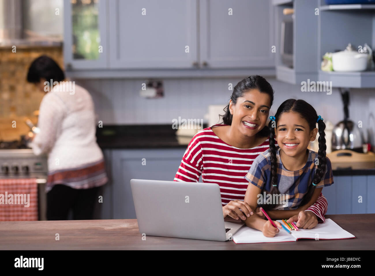 Ritratto di ragazza sorridente con la madre a studiare in cucina a casa Foto Stock
