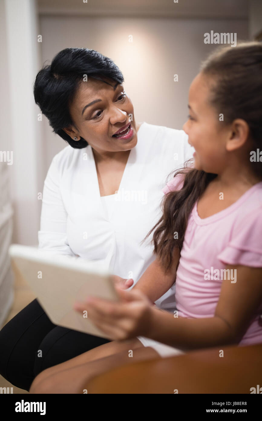 Donna seduta con il nipote utilizzando tavoletta digitale in casa Foto Stock