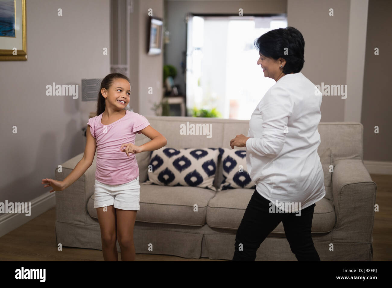 Ragazza sorridente ballando con la nonna a casa Foto Stock