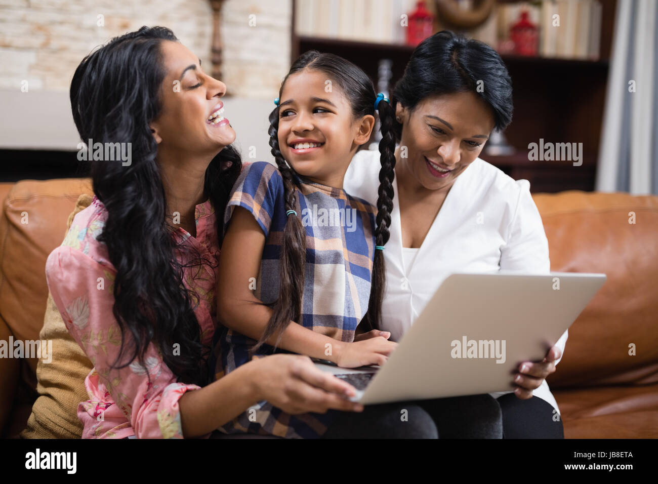 Felice multi-generazione famiglia utilizzando laptop stando seduti insieme sul divano di casa Foto Stock