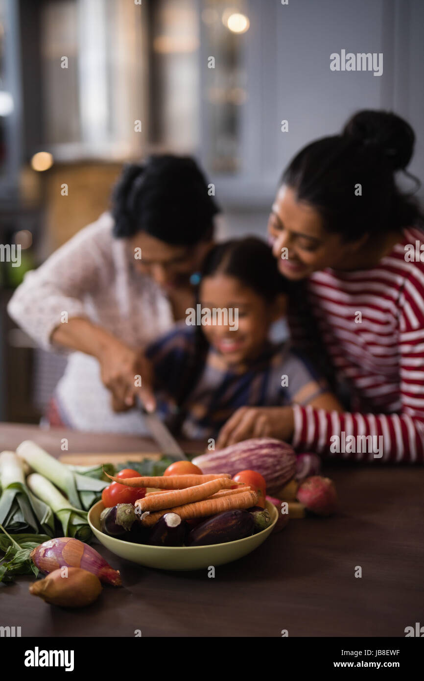 Verdure sulla tavola contro multi-famiglia di generazione di preparare il cibo in cucina a casa Foto Stock