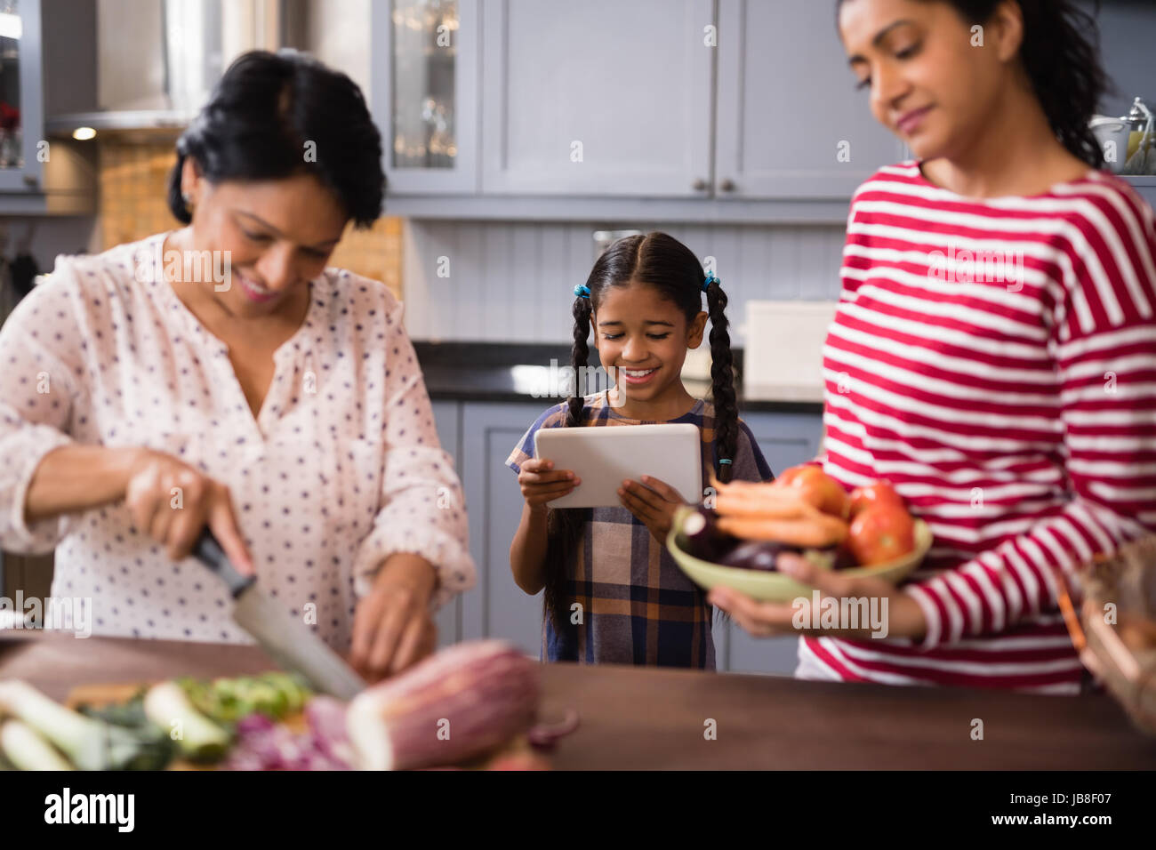 Felice multi-famiglia di generazione di preparare il cibo insieme nella cucina di casa Foto Stock