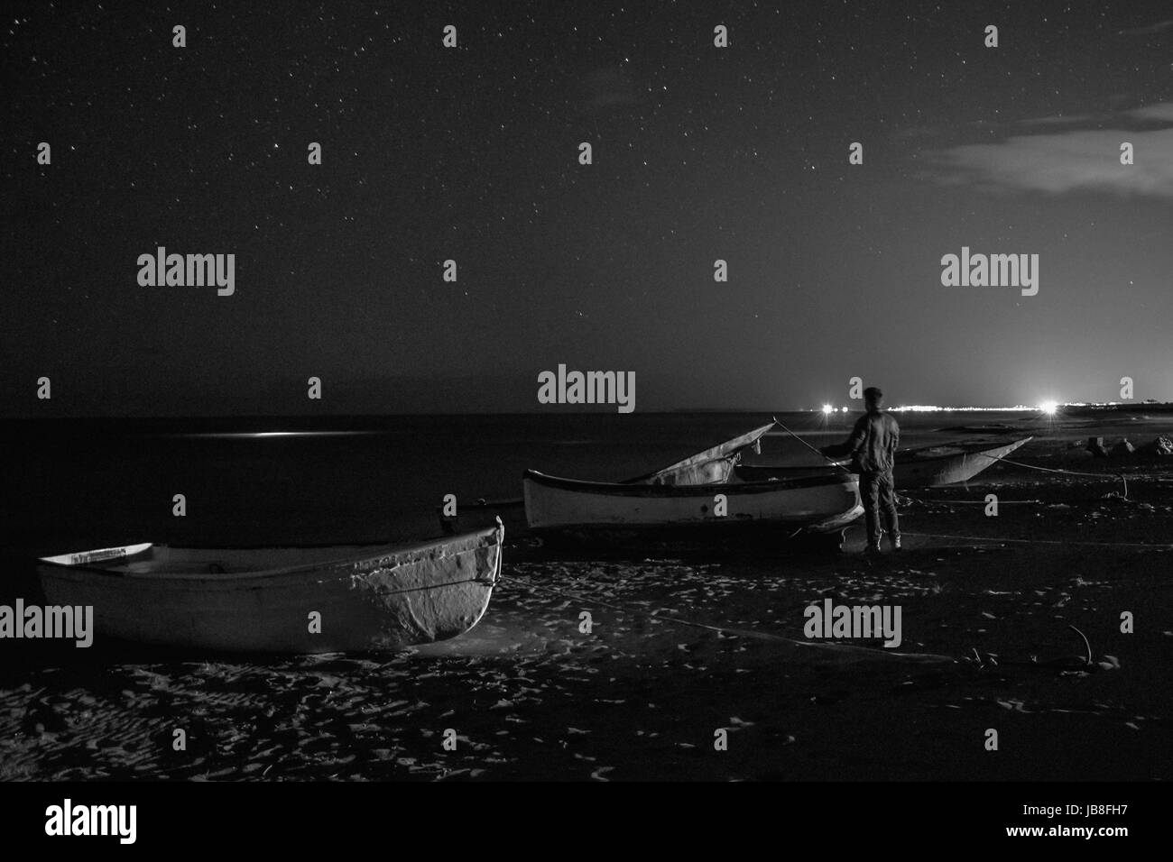 L uomo al centro delle barche guarda il cielo stellato Foto Stock