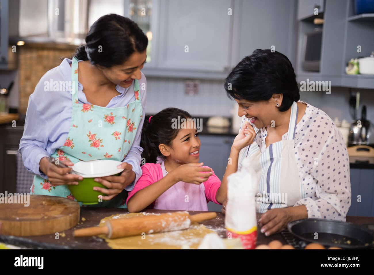 Ragazza sorridente con la madre e nonna di preparare il cibo in cucina a casa Foto Stock
