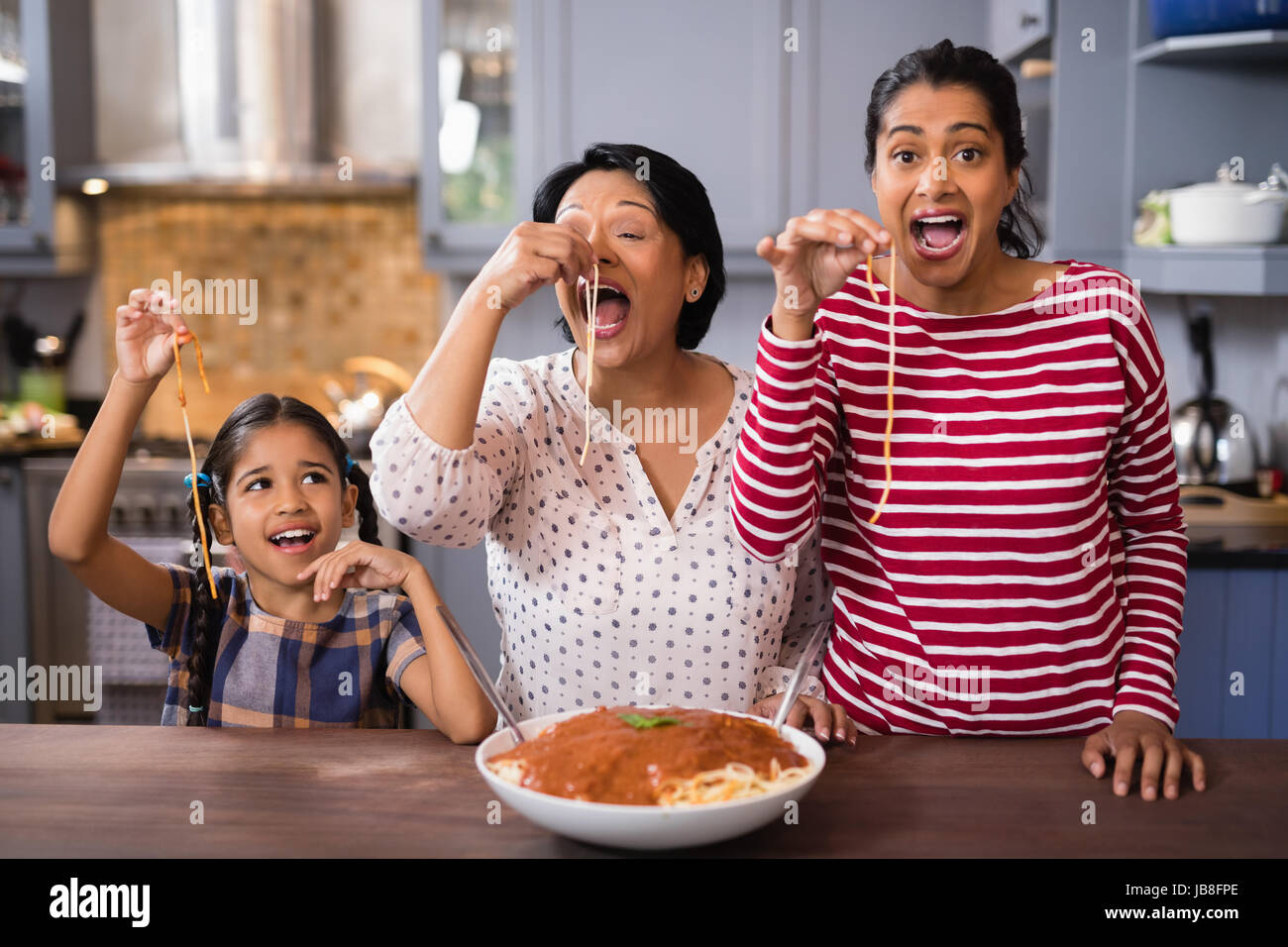 Felice multi-generazione famiglia mangiare spaghetti in cucina a casa Foto Stock