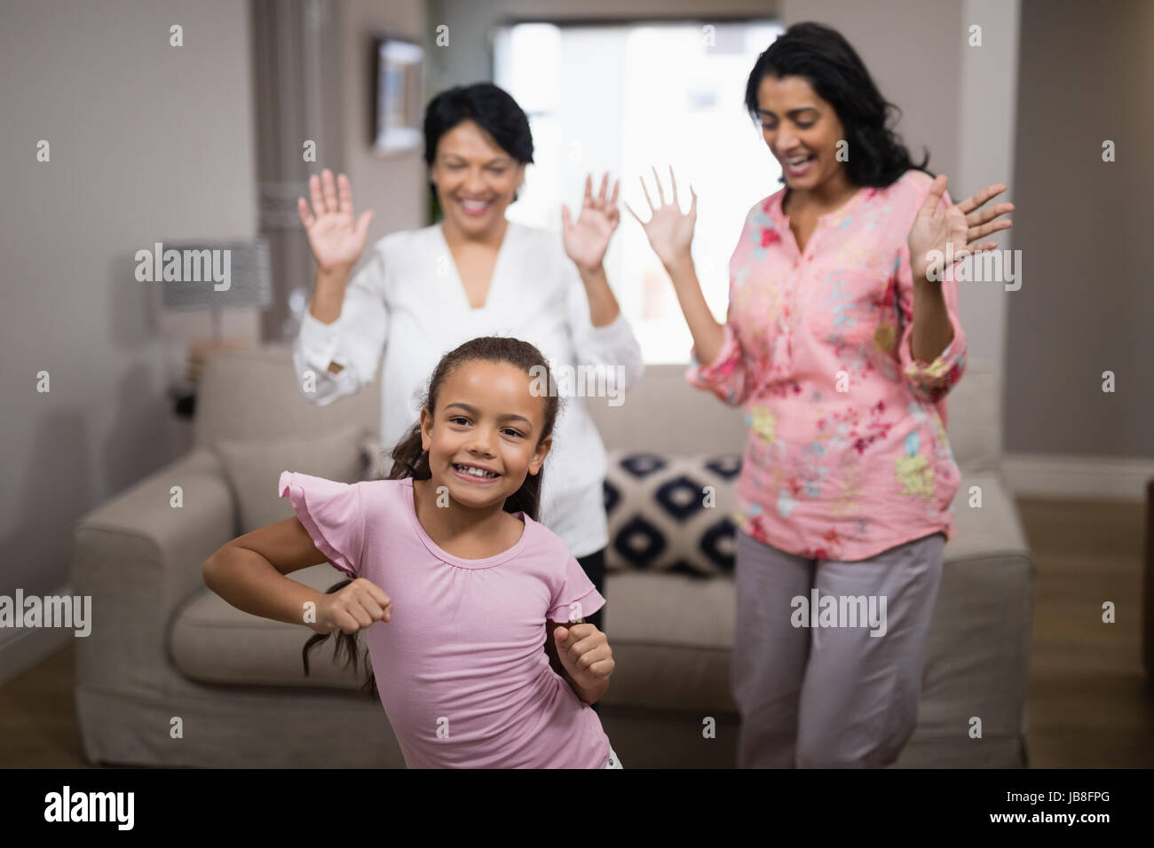 Ritratto di ragazza sorridente ballando con la famiglia a casa Foto Stock