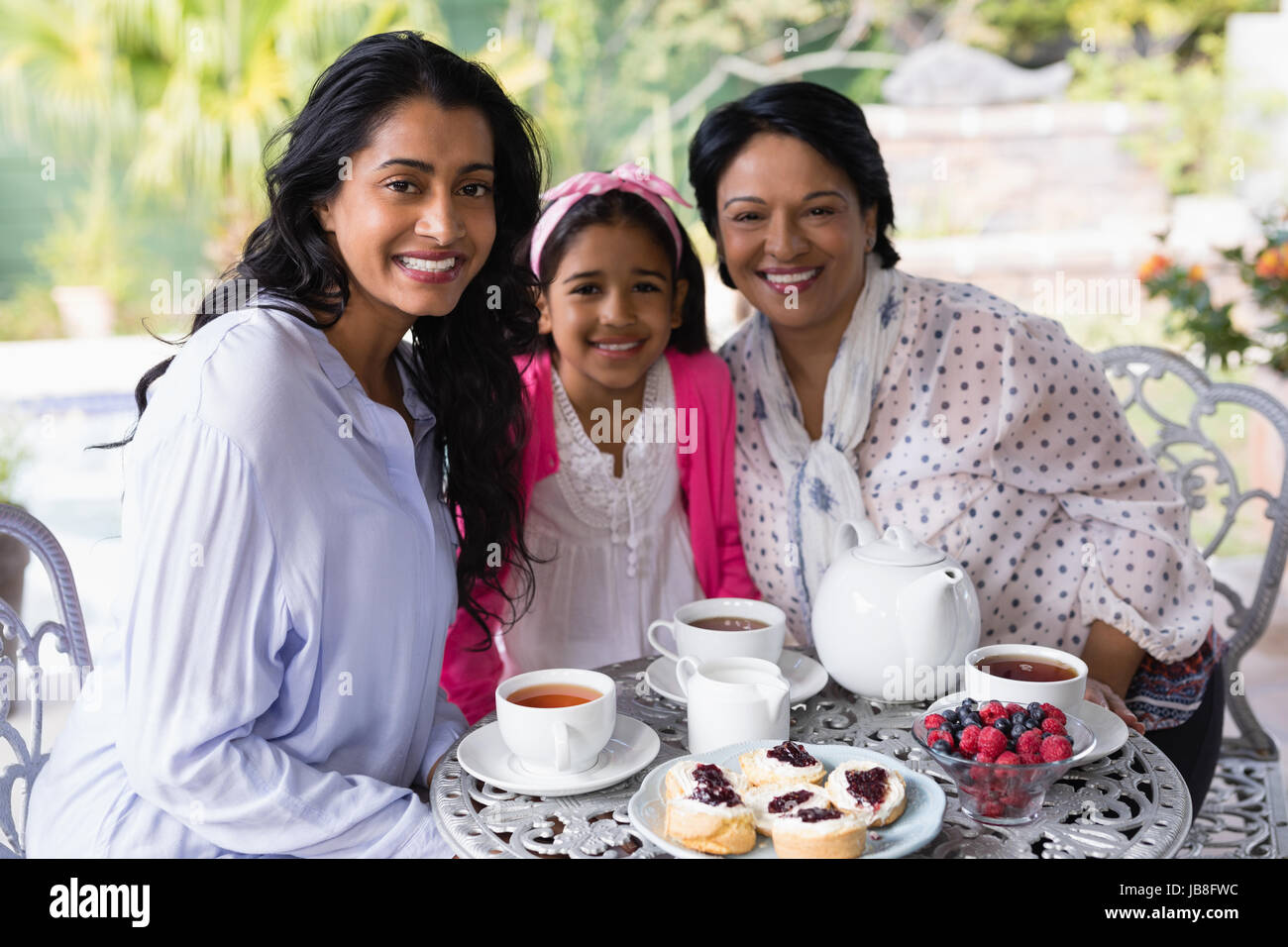 Ritratto di sorridere multi-generazione famiglia seduti insieme da tavolo per la colazione a casa Foto Stock