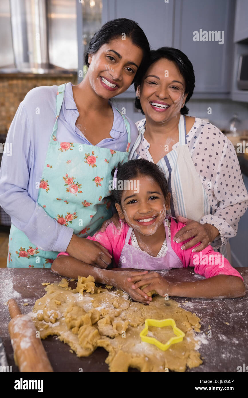 Ritratto di sorridere multi-generazione permanente della famiglia da impasto in cucina a casa Foto Stock