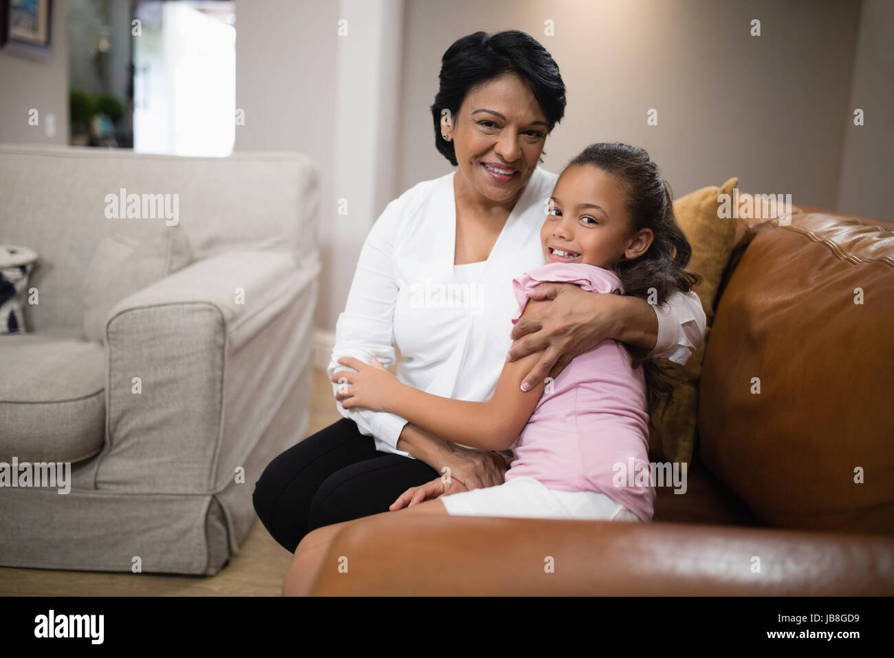 Ritratto di Nonna e nipote abbracciando comodamente seduti sul divano di casa Foto Stock