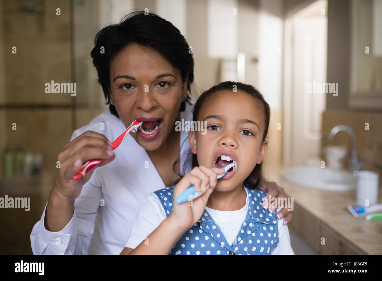 Ritratto di ragazza sorridente e nonna spazzolare i denti in bagno Foto Stock