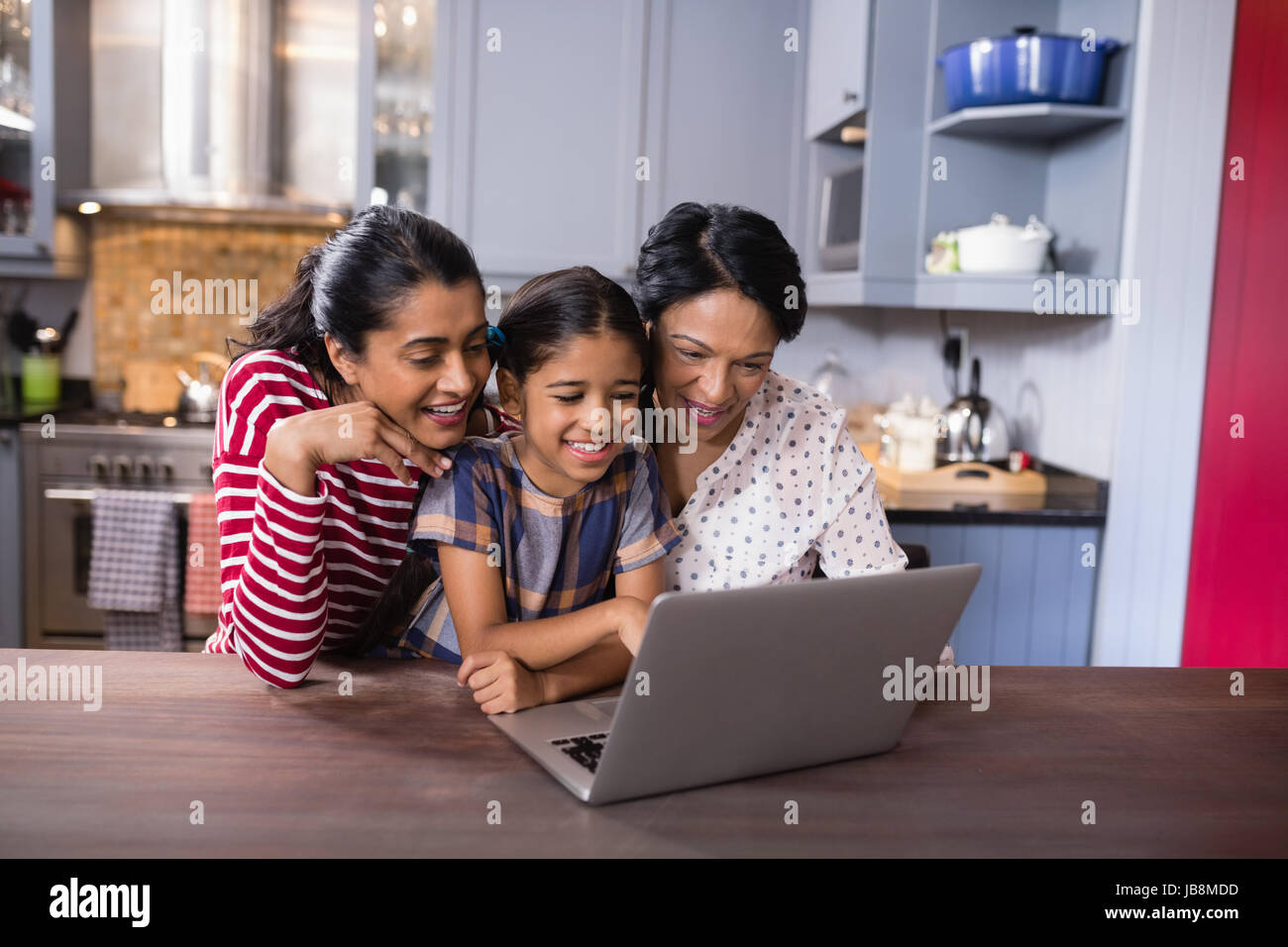 Sorridente multi-generazione famiglia utilizzando laptop insieme nella cucina di casa Foto Stock