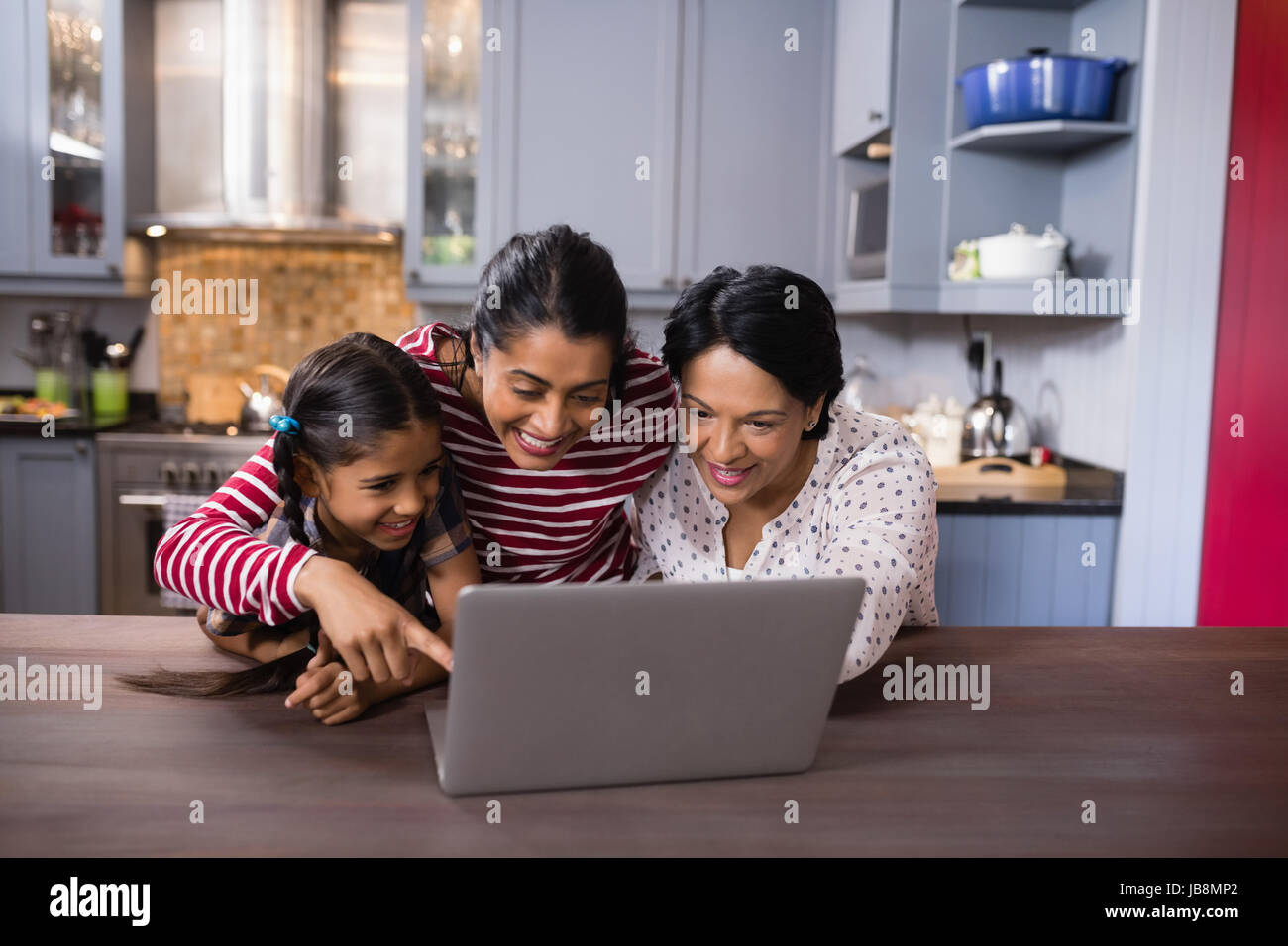 Felice multi-generazione famiglia utilizzando laptop insieme nella cucina di casa Foto Stock