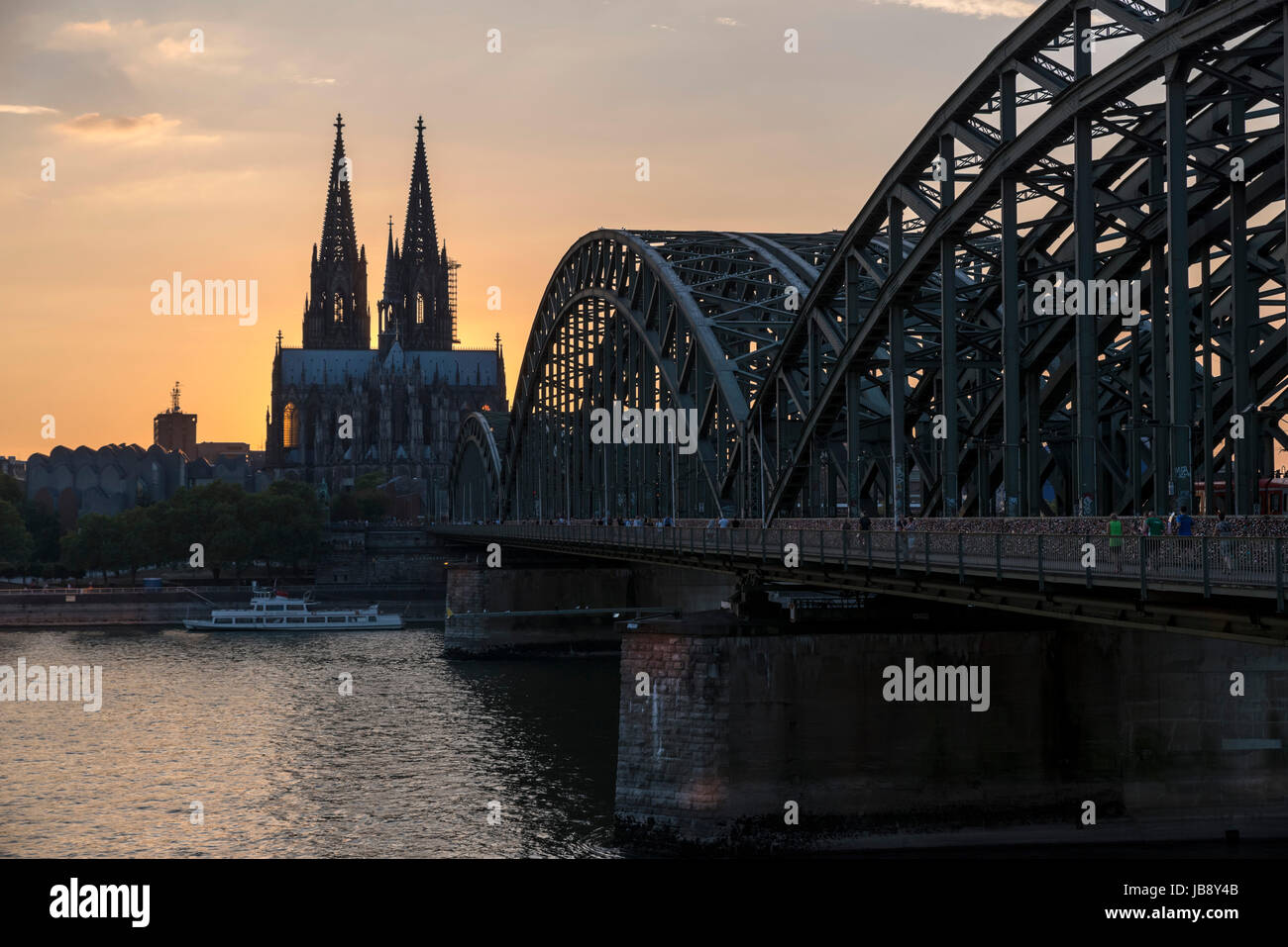 Il fiume Reno al tramonto, guardando verso la cattedrale di Colonia (Kölner Dom) con il ponte di Hohenzollern Hohenzollernbrücke) in primo piano, Colonia, Germania Foto Stock