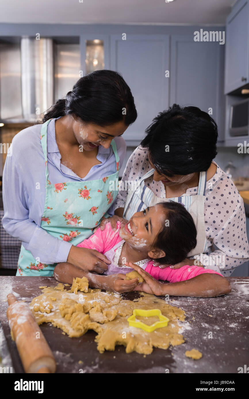 Sorridente multi-generazione permanente della famiglia da impasto in cucina a casa Foto Stock